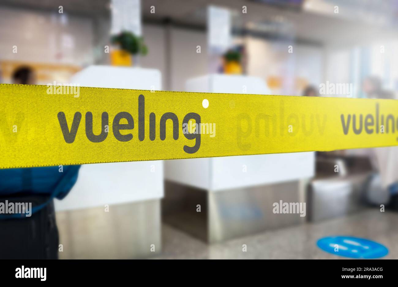 Madrid, SP, June 21 2023: Yellow retractable belt barrier with grey Vueling airlines logo. Spanish low-cost airline operating primarily in Europe. Tra Stock Photo