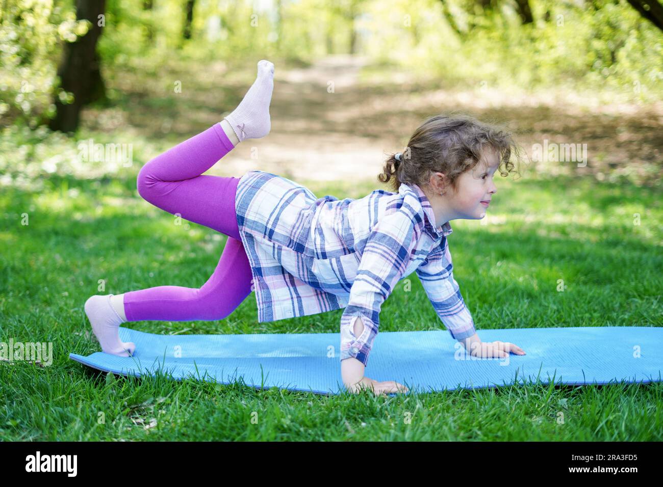 Child Girl doing yoga exercises in the park, healthy lifestyle
