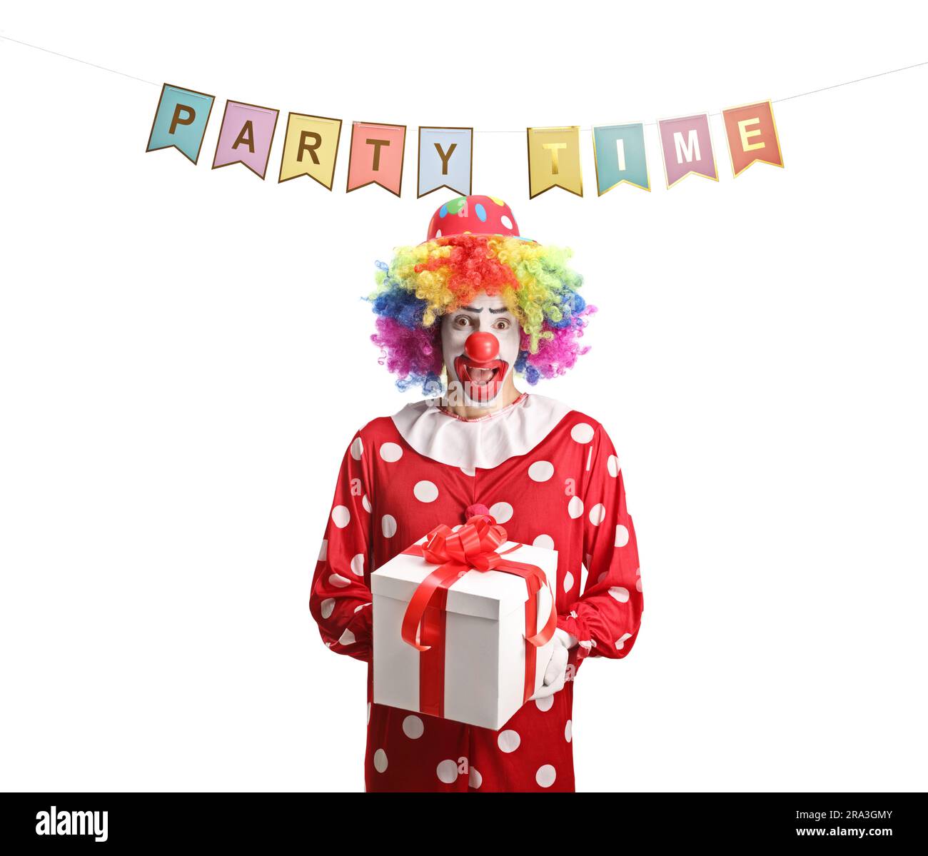 Clown in a red costume under party flags holding a present box isolated on white background Stock Photo