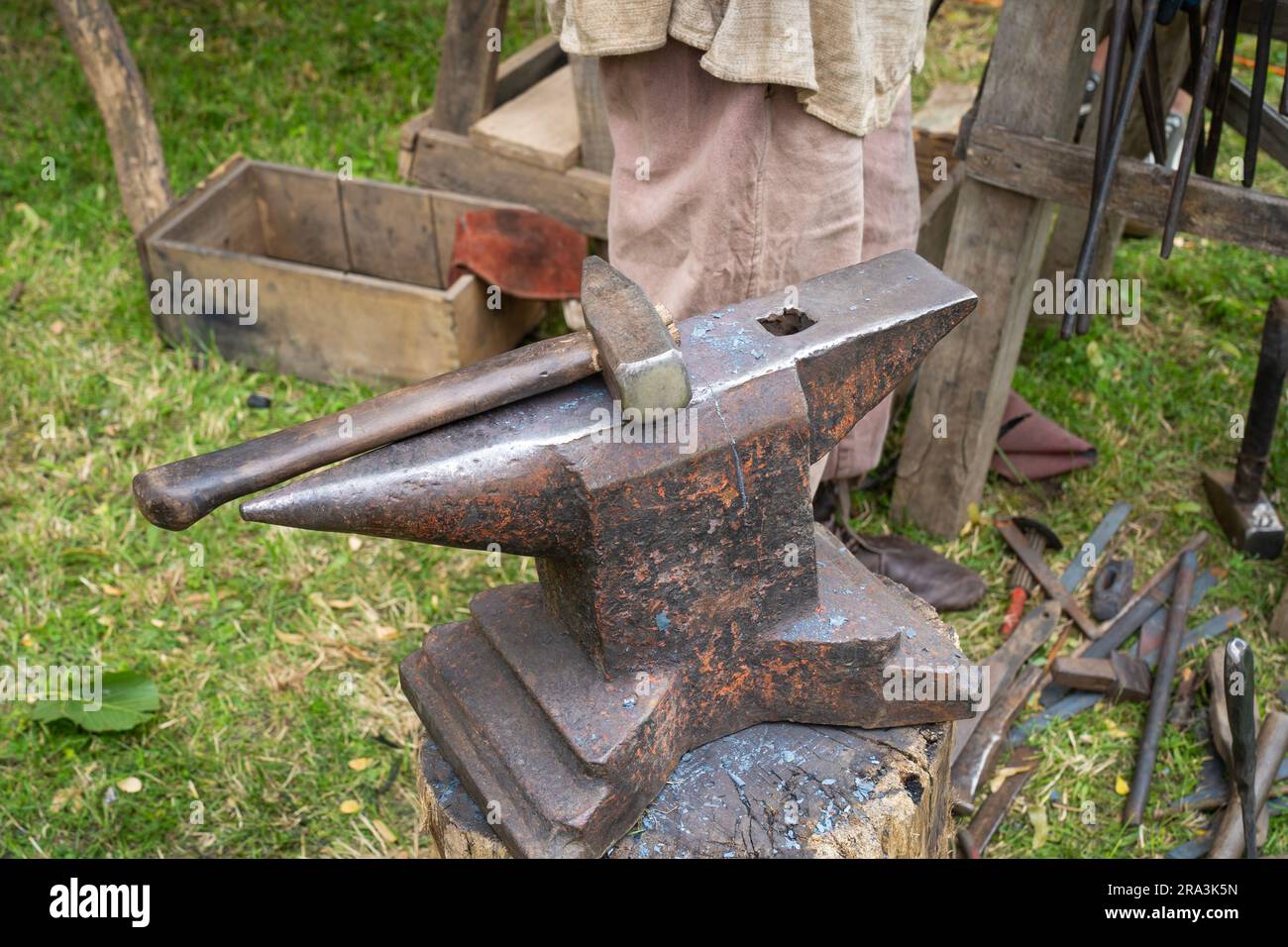 Blacksmith's anvil with hammer in the background with metal tools Stock Photo