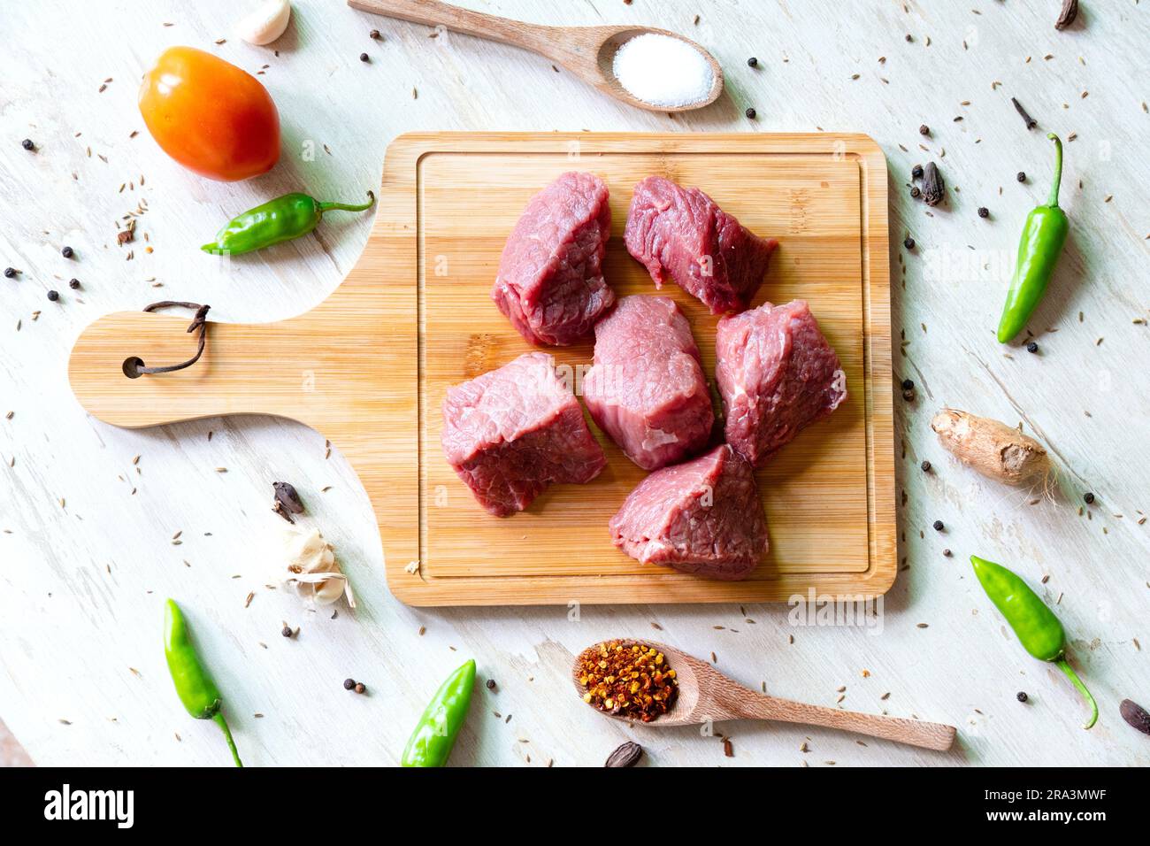 https://c8.alamy.com/comp/2RA3MWF/raw-beef-meat-on-wooden-cutting-board-for-cooking-stew-or-other-meat-dish-on-white-background-top-view-2RA3MWF.jpg