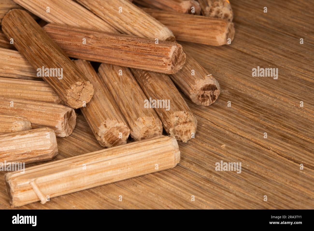 pile of oak dowel pins on oak  background, dowel pins used to join two pieces of wood, joint, joinery Stock Photo