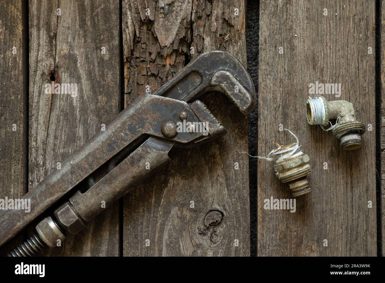 old rusty gas wrench lies on a wooden table close-up Stock Photo