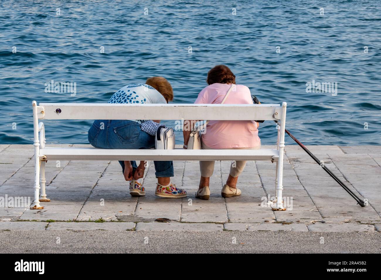 Two Older Retired Ladies Or Women Sitting On A Bench Together At The two-older-retired-ladies-or-women-sitting-on-a-bench-together-at-the