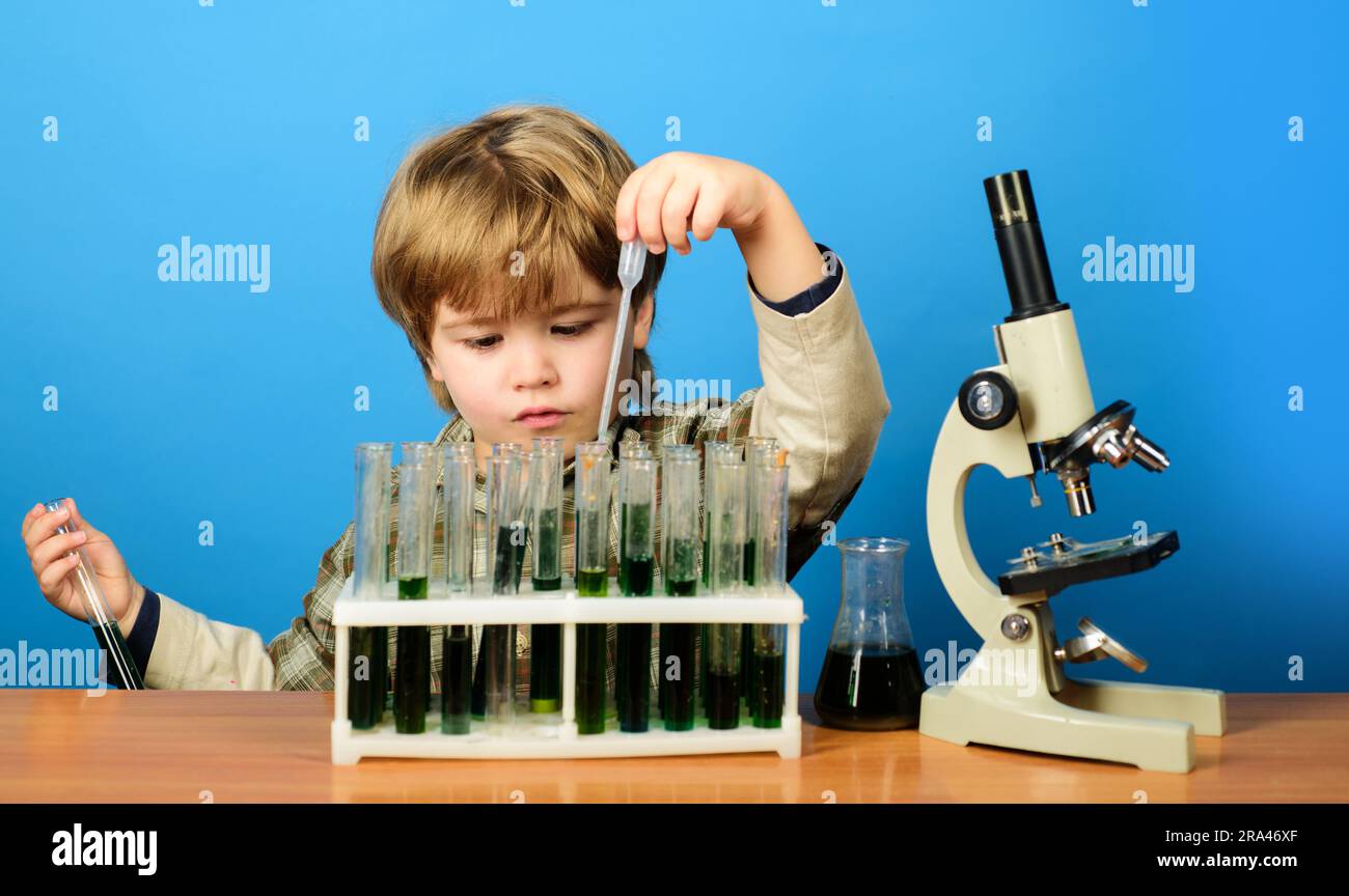 Smart boy working with test tubes and microscope in school classroom. Child study biology chemistry. Educational experiment. School subject. Kid boy Stock Photo