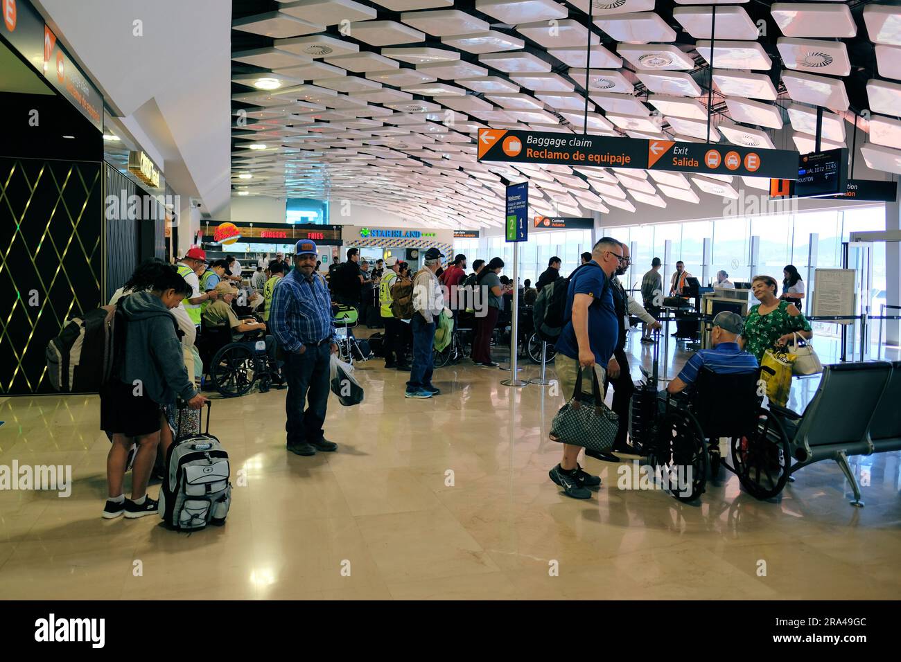 Passengers waiting to board a flight at Bajio International Airport in Silao, Guanajuato; travelers with luggage at boarding gate; wheel chair Stock Photo
