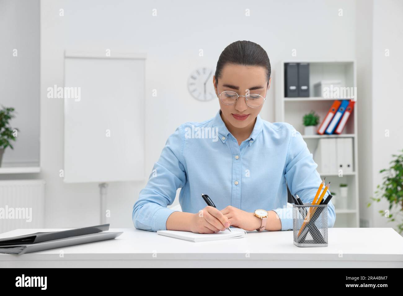 Young female intern working at table in office Stock Photo