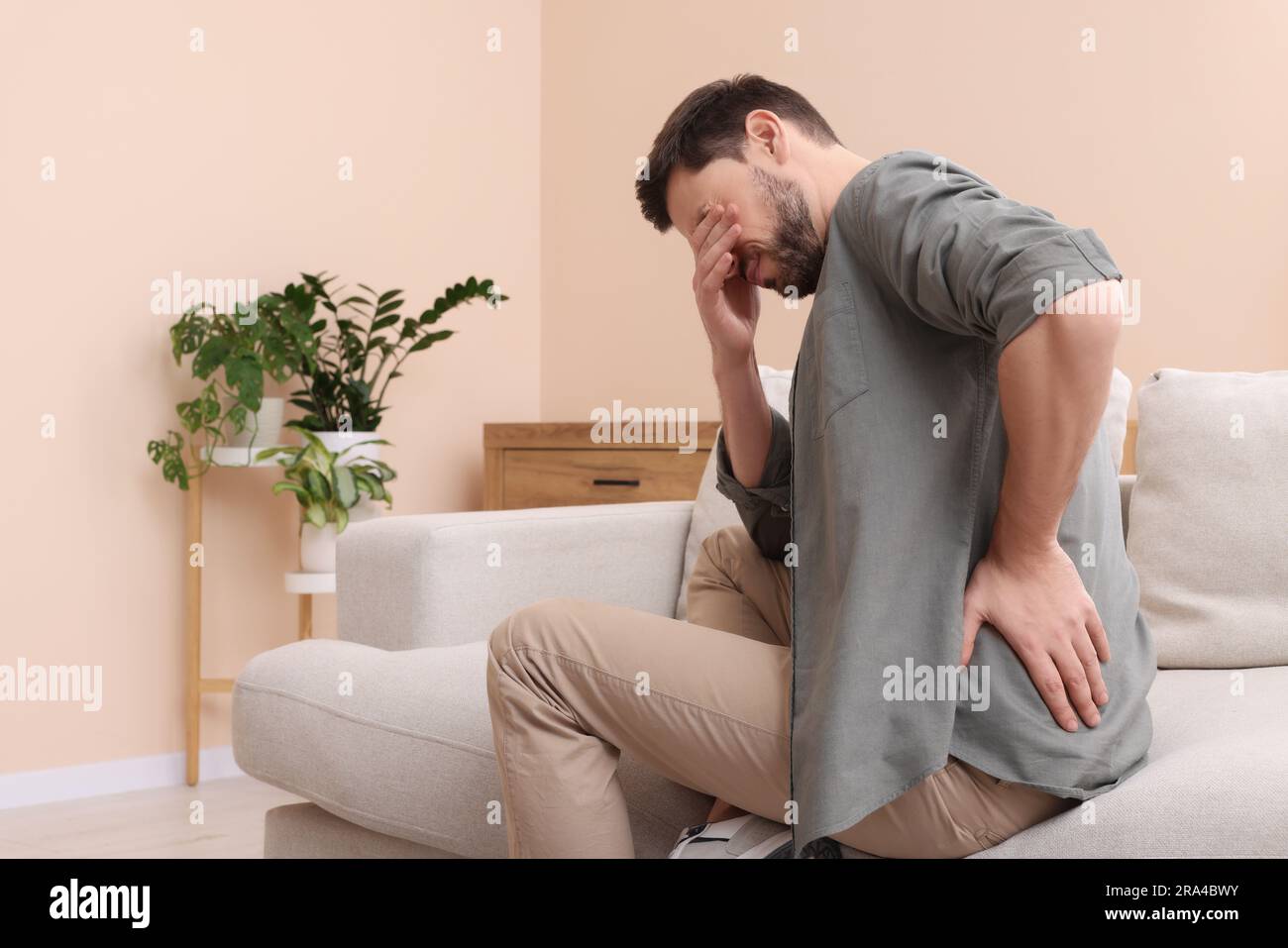 Man suffering from pain in his back at home, space for text. Arthritis