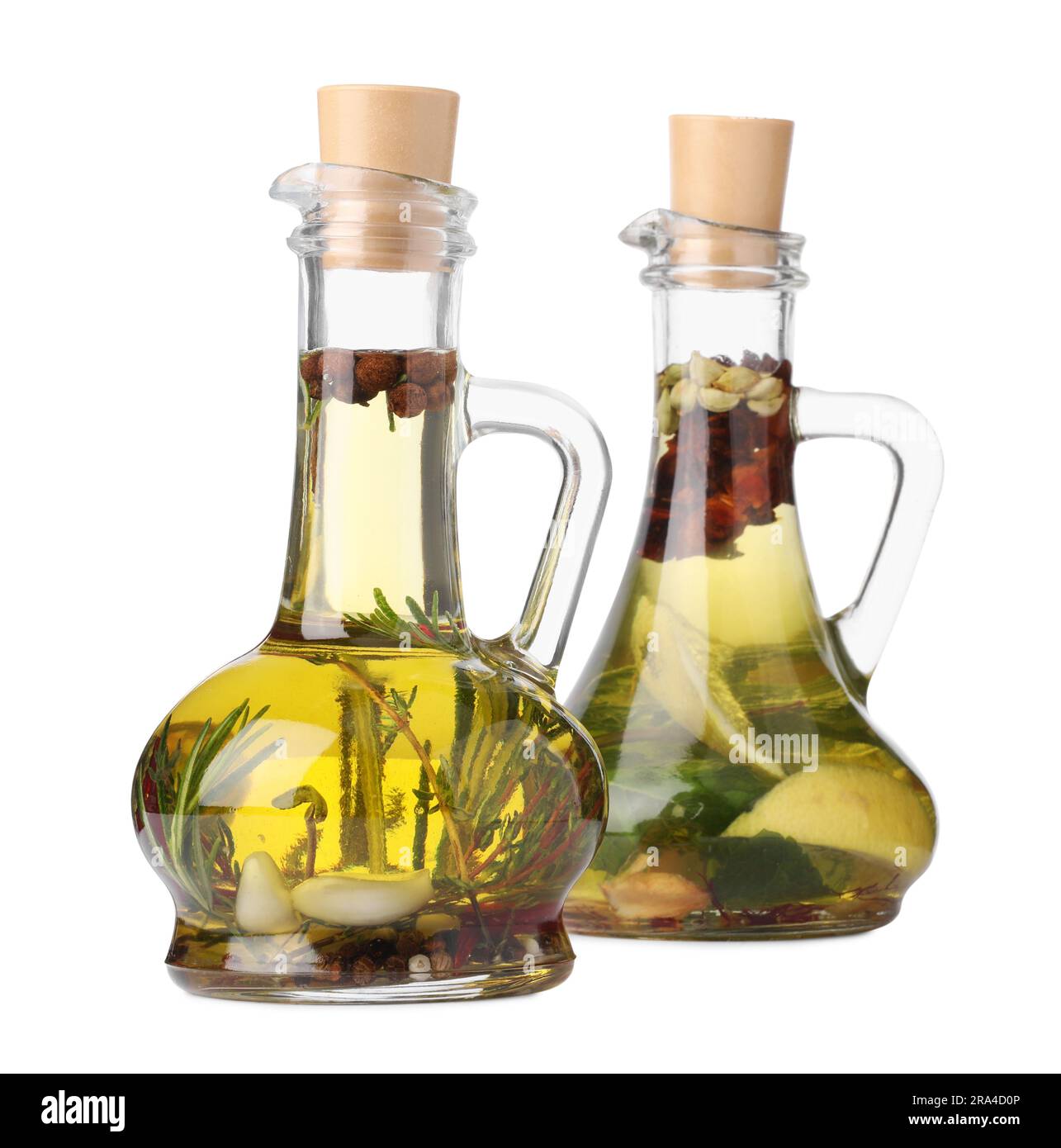 Glass jugs of cooking oils with spices and herbs on white background
