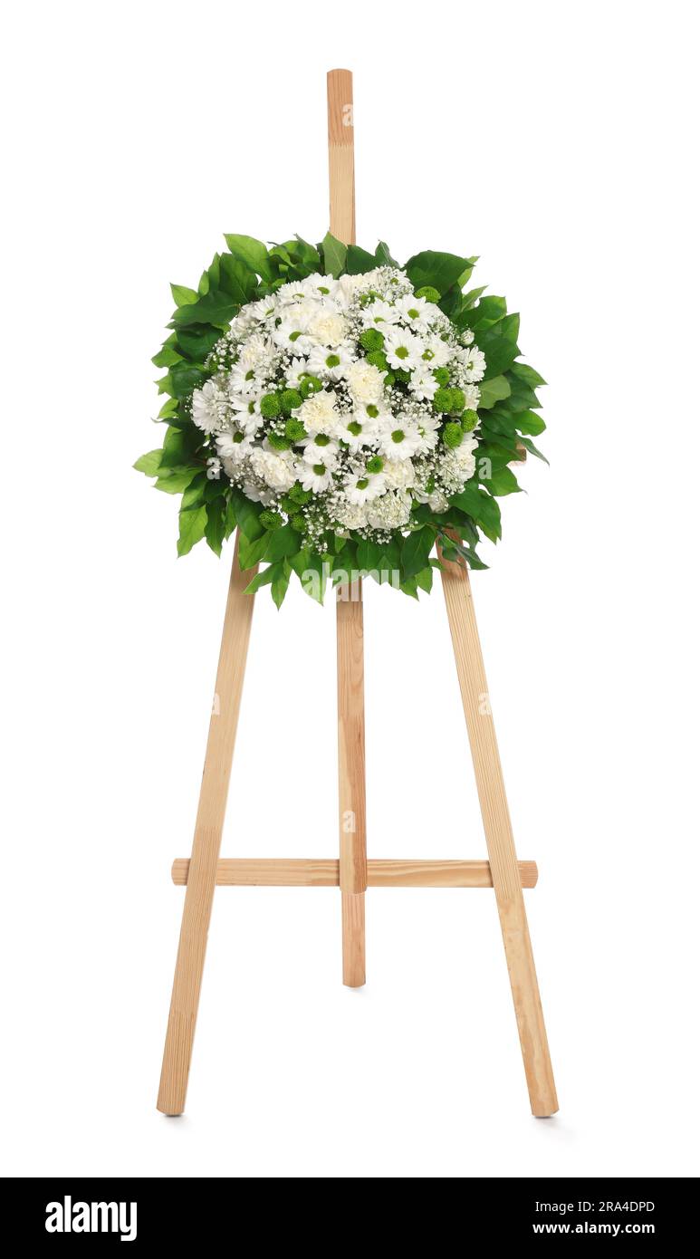 Funeral wreath of flowers on wooden stand against white background Stock Photo