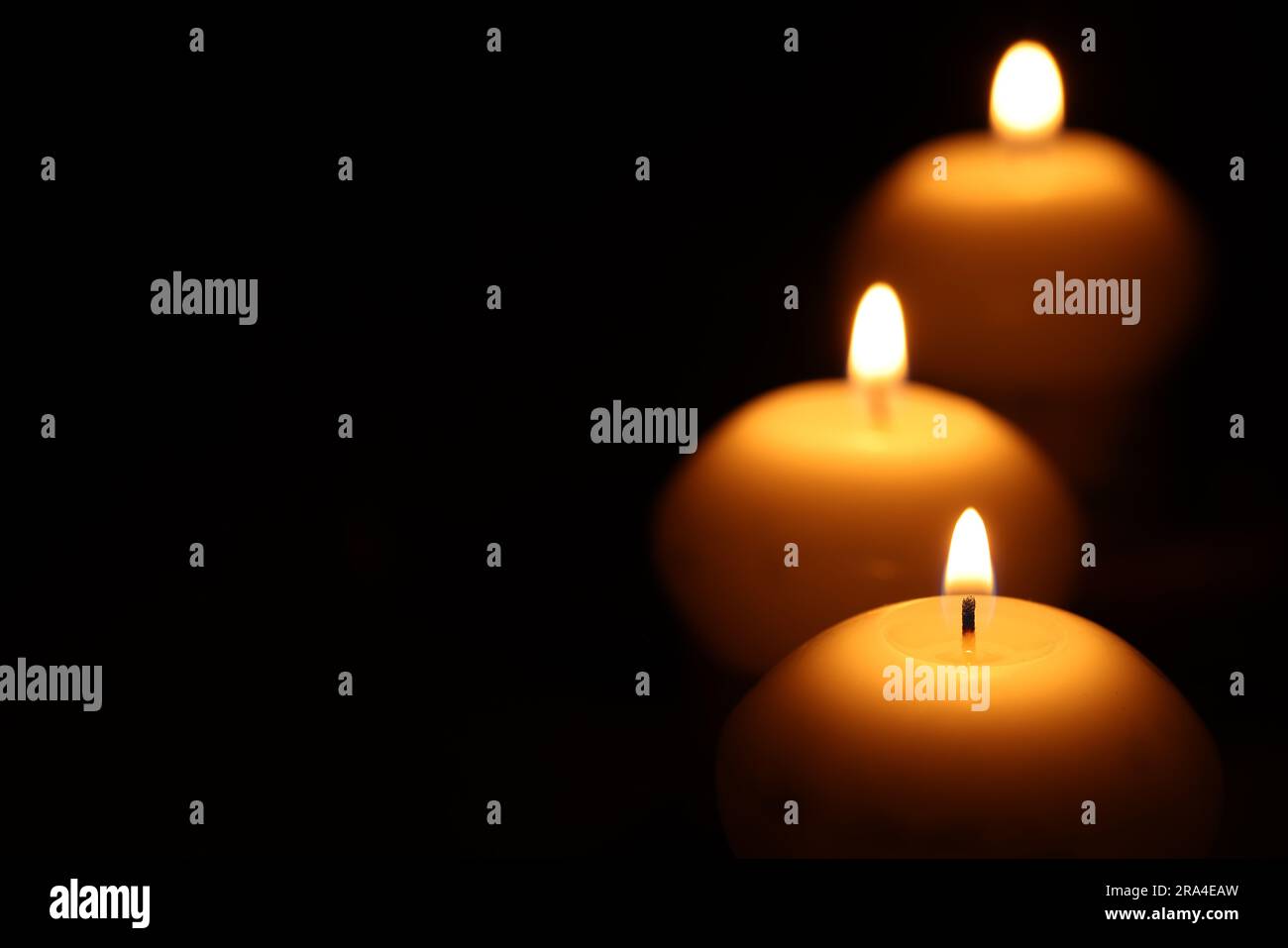 Burning wax candles on black background, closeup. Space for text Stock ...