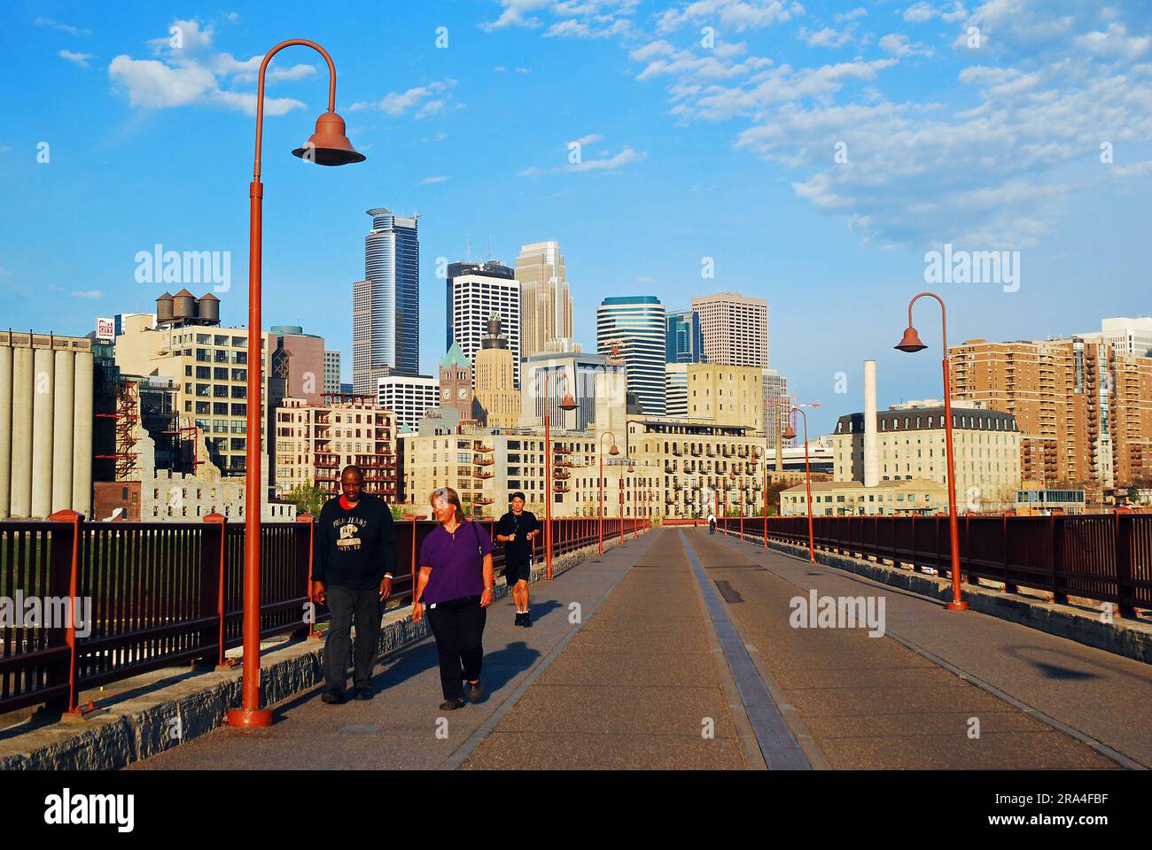 Folks take an early morning walk on the Stone Arch Bridge, a pedestrian only crossing in Minneapolis, Minnesota Stock Photo