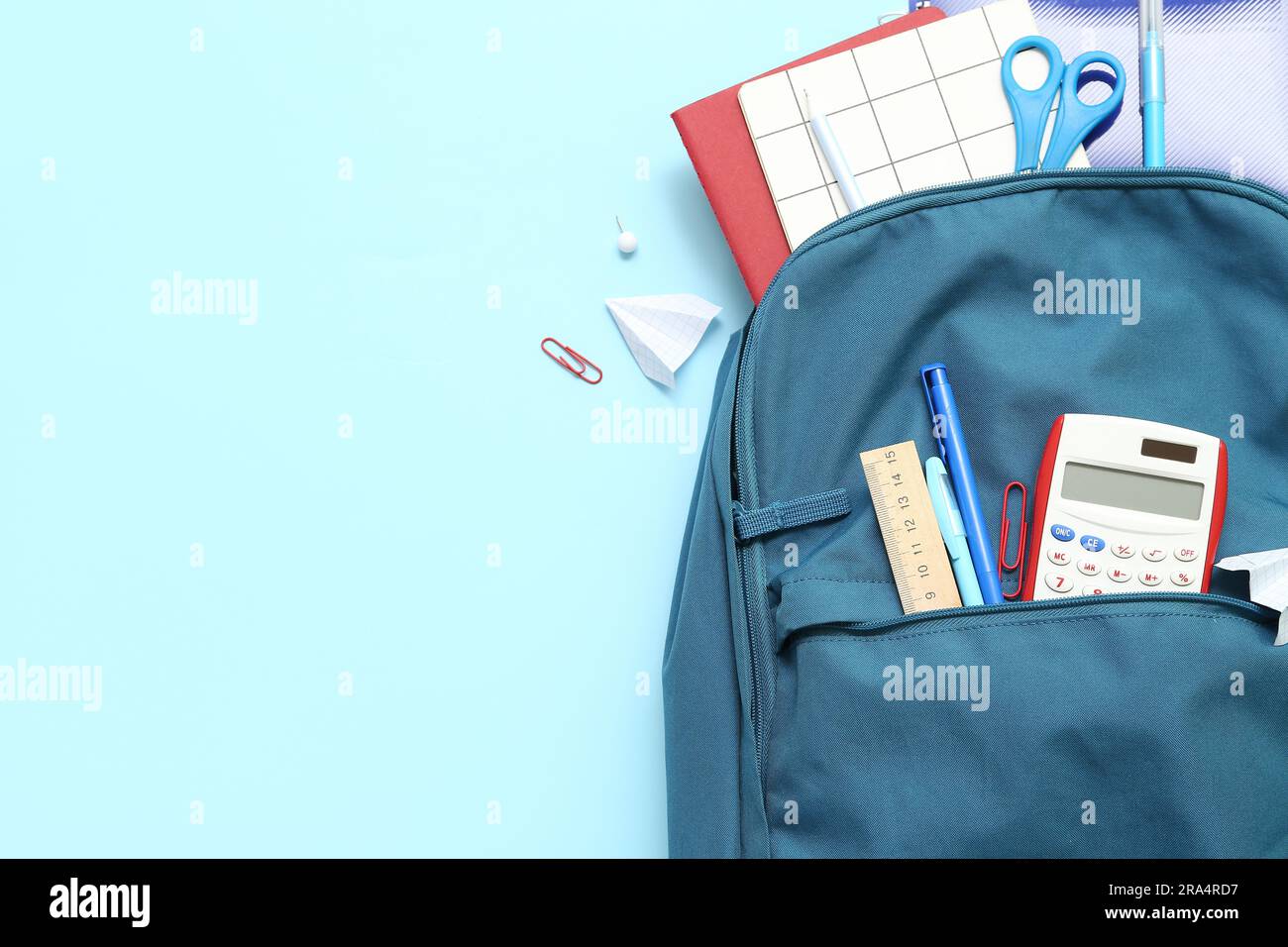 School backpack with different stationery on blue background Stock Photo