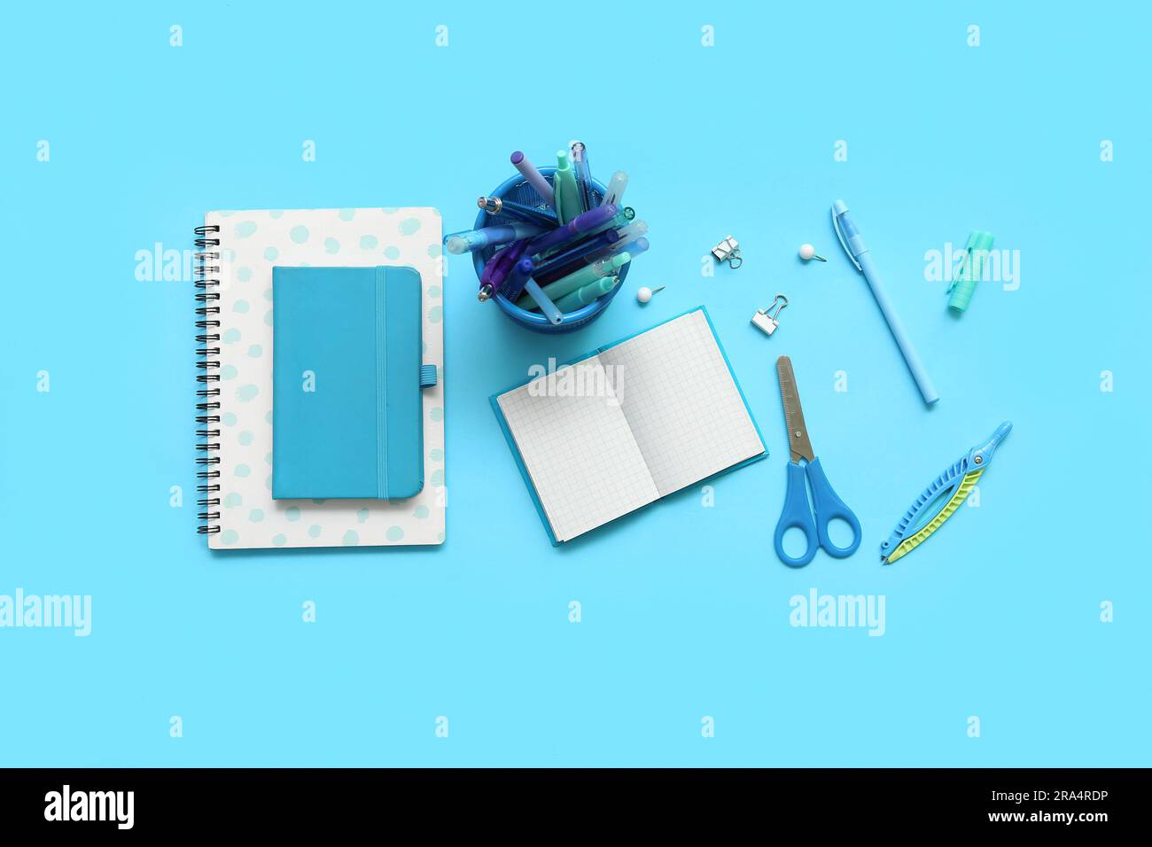Composition with notebooks and different school stationery on blue background Stock Photo