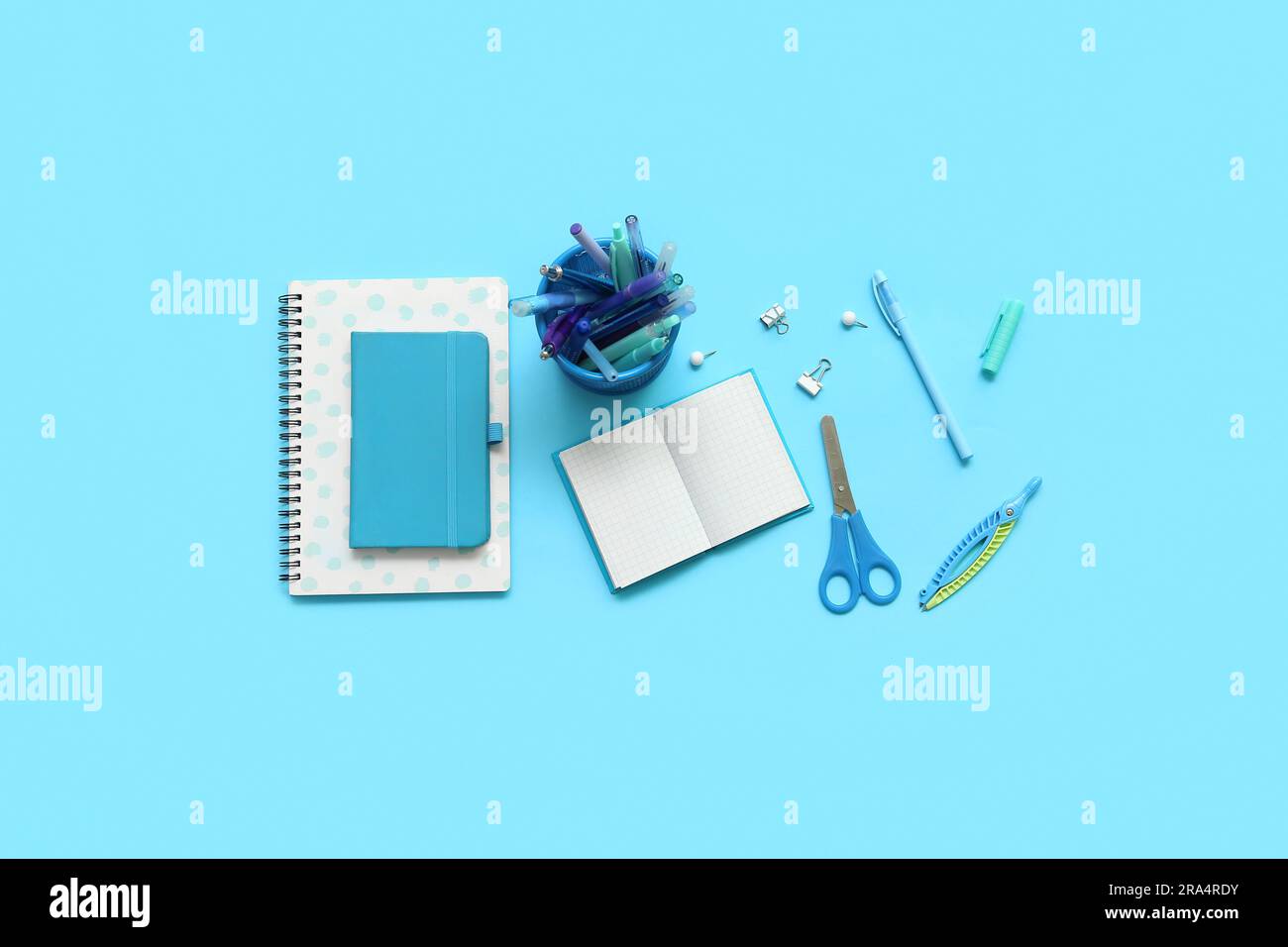 Composition with notebooks and different school stationery on blue background Stock Photo