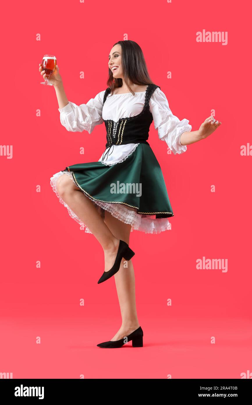 Beautiful Octoberfest waitress with beer dancing on red background ...