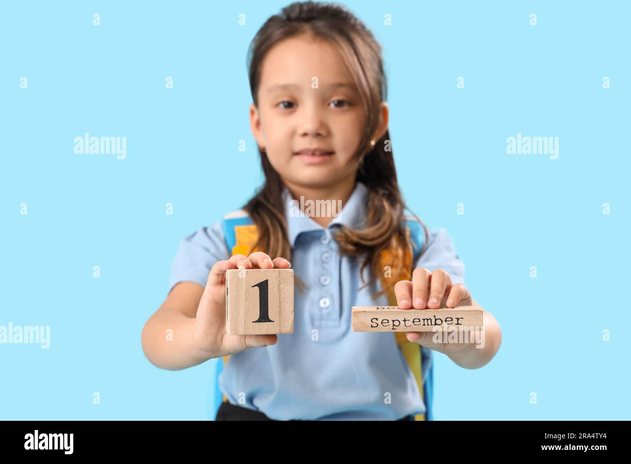 Little schoolgirl with calendar on light blue background Stock Photo ...