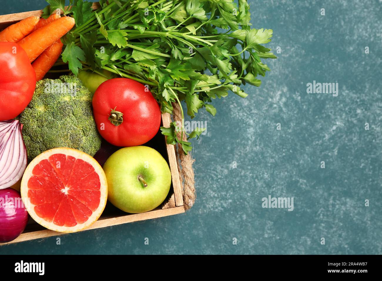 Wooden box with different fresh fruits and vegetables on green ...