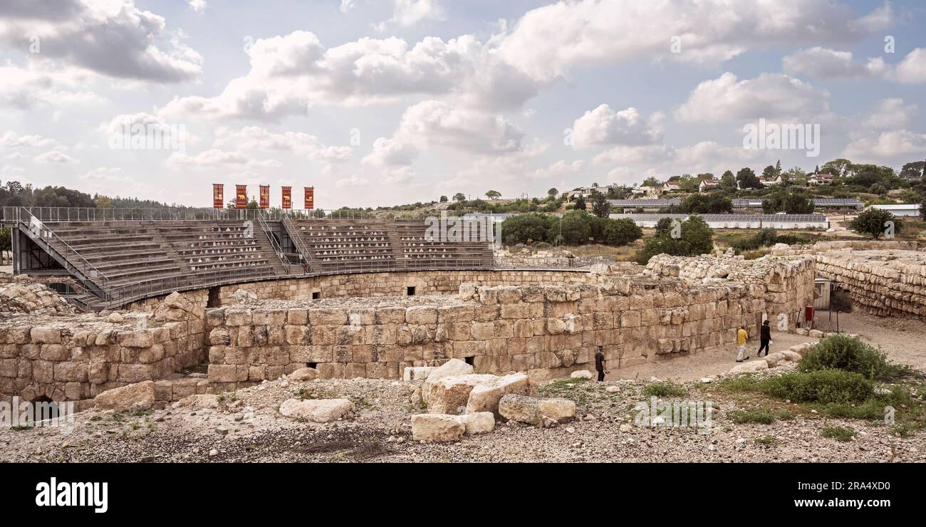 reconstructed ancient roman amphitheater at beit guvrin park in israel with a modern settlement and partly cloudy sky in the background Stock Photo