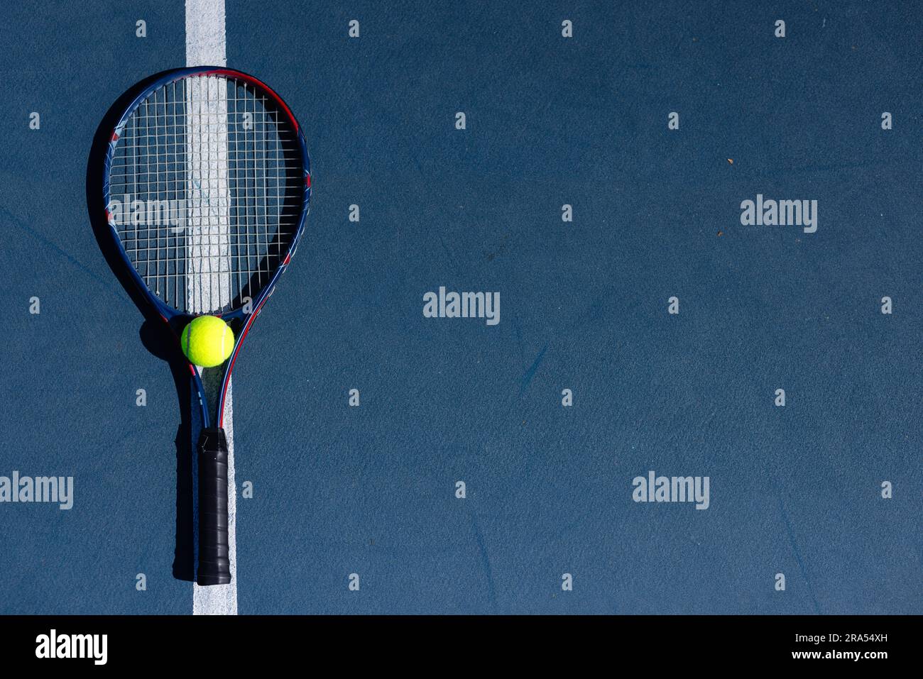 Overhead of tennis ball and tennis racket lying on tennis court on
