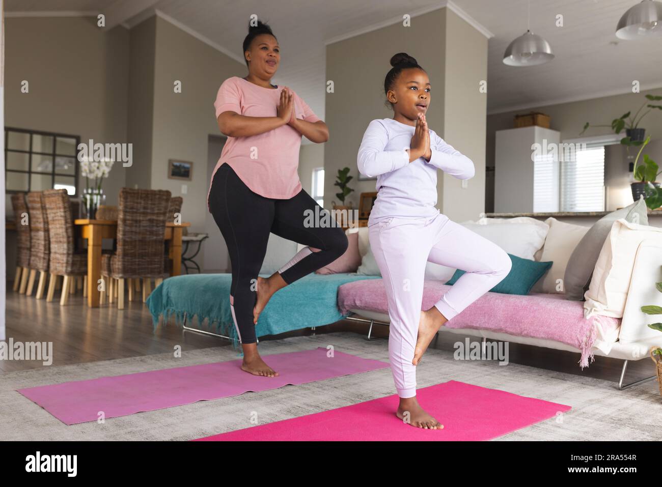African american mother and daughter doing yoga and meditating in ...