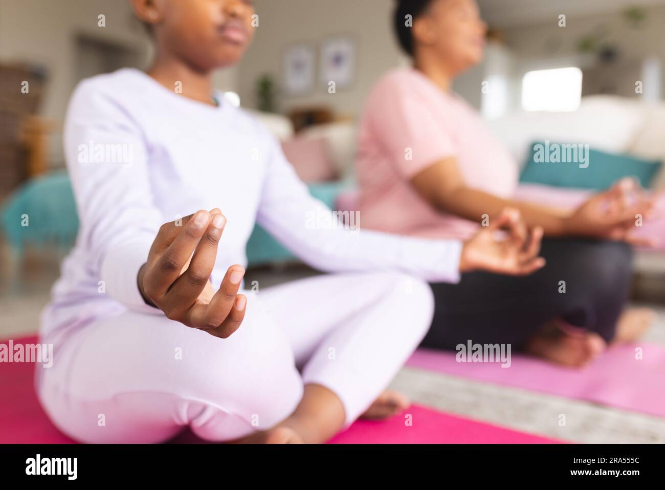 African american mother and daughter doing yoga and meditating in ...