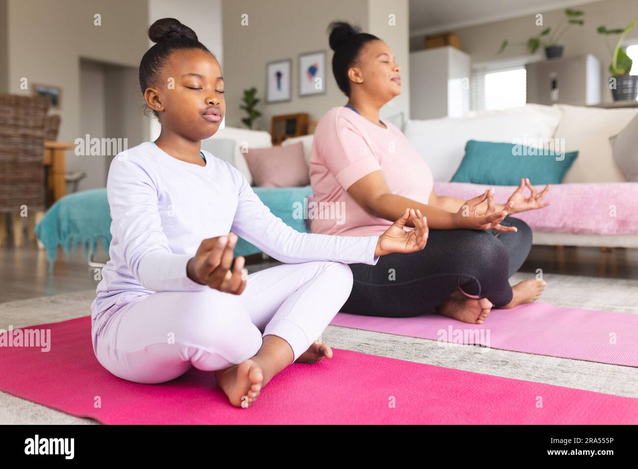 African american mother and daughter doing yoga and meditating in ...