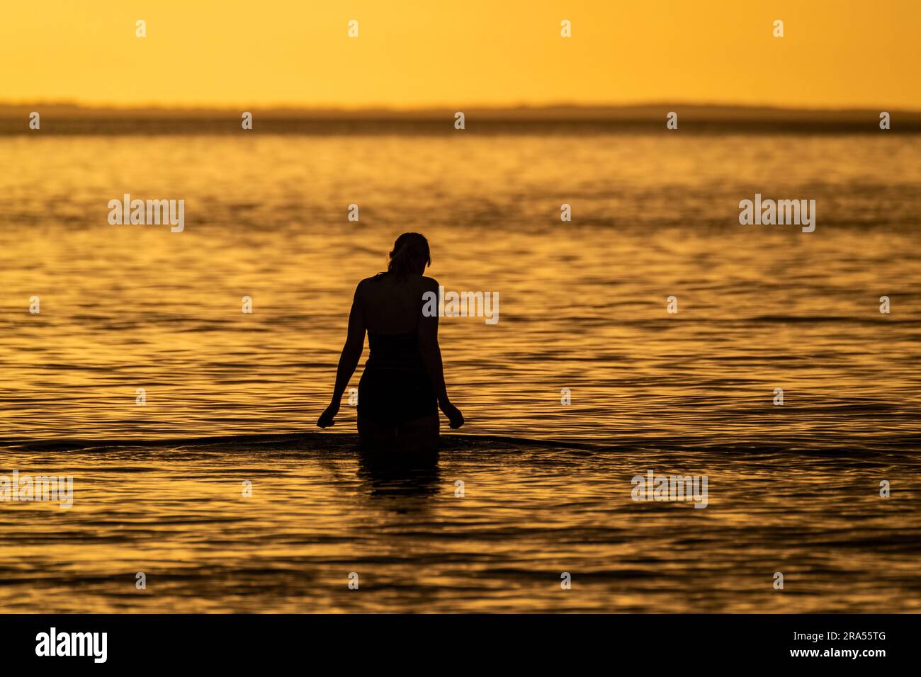 Silhouette of female swimmer going into the Atlantic ocean in Ireland. Stock Photo