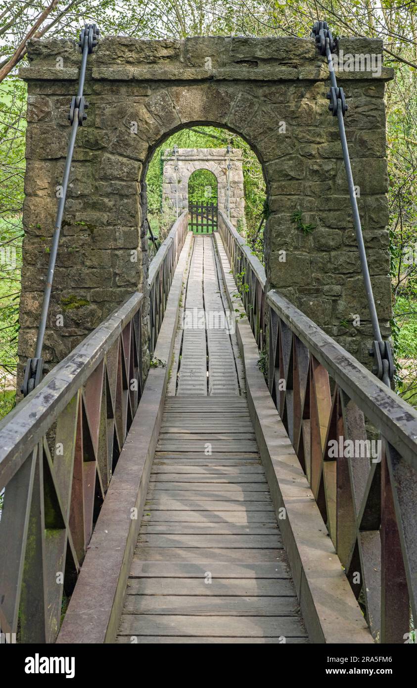 A wood and stone footbridge crossing over the River Kent in the Lake District near the busy town of Kendal in Cumbria Stock Photo