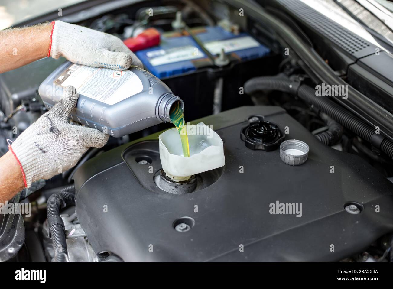 changing the oil in a car engine. A car mechanic pours engine oil