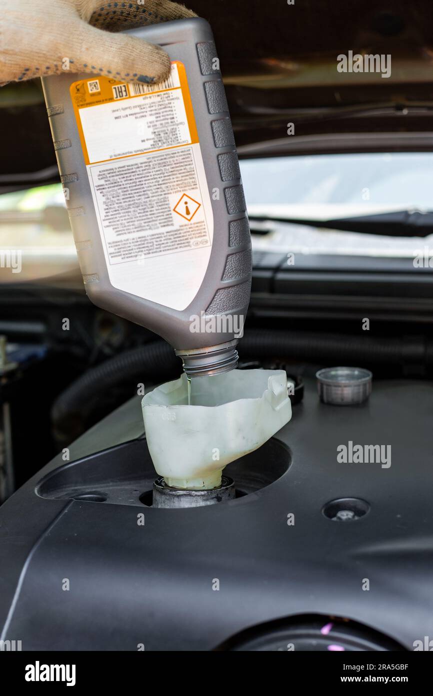 changing the oil in a car engine. A car mechanic pours engine oil