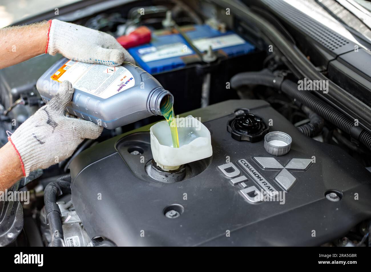 Mitsubishi engine oil change. A car mechanic pours Mobile engine oil
