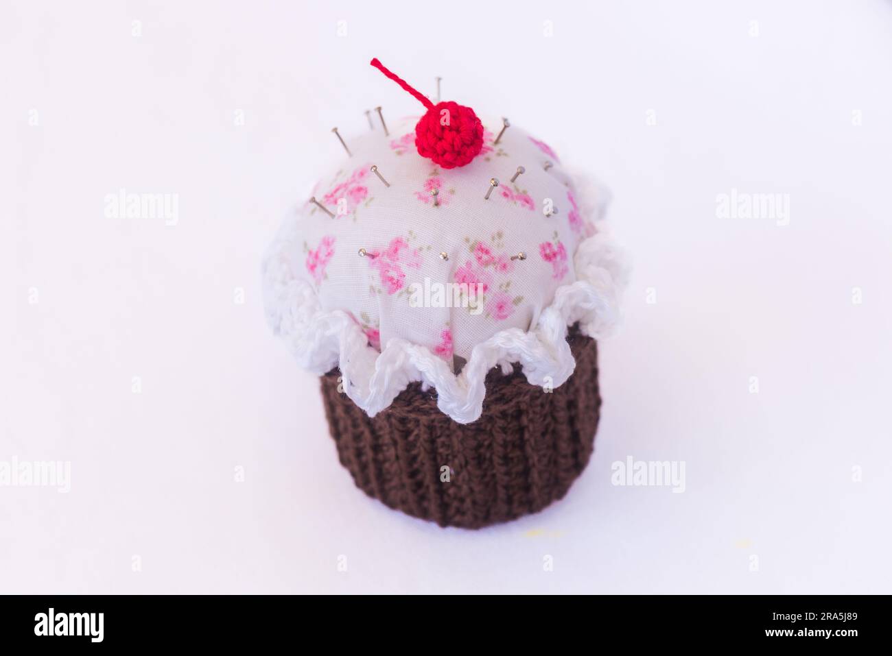 details of a cupcake-shaped pincushion, on a white background Stock Photo
