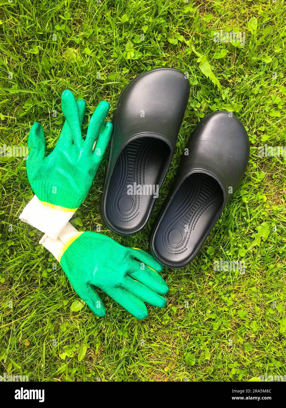 rubber galoshes and green construction gloves lie on the green grass