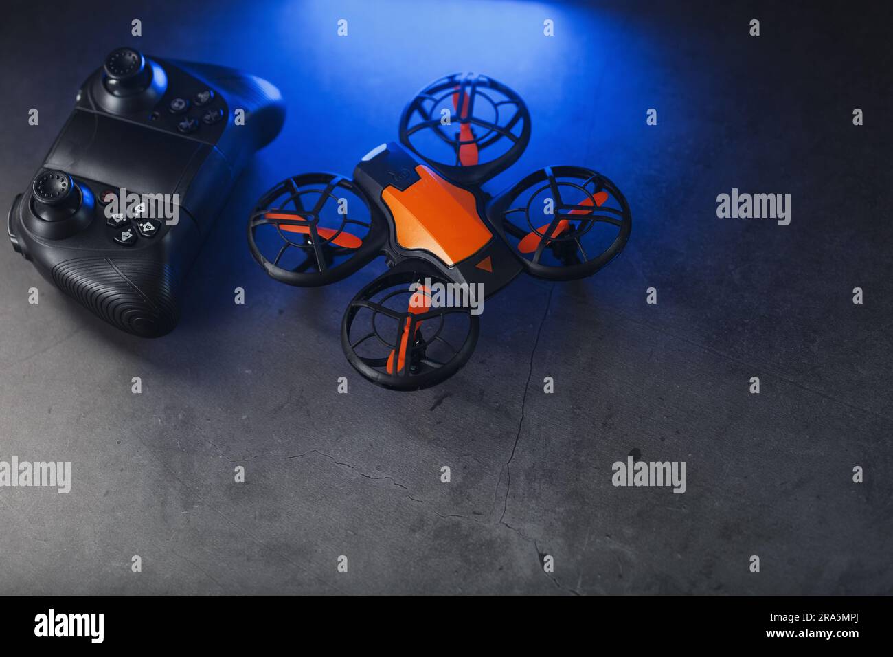 Quadcopter drone with joystick control and blue neon backlight, on a dark textured background Stock Photo