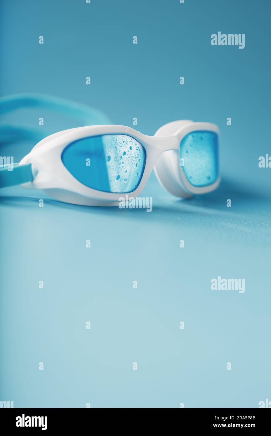 White swimming goggles on a blue background in a minimalist style with free space Stock Photo