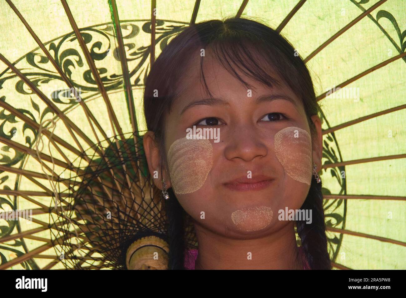 Young Burmese woman with parasol and thanaka paste on her face, Bagan