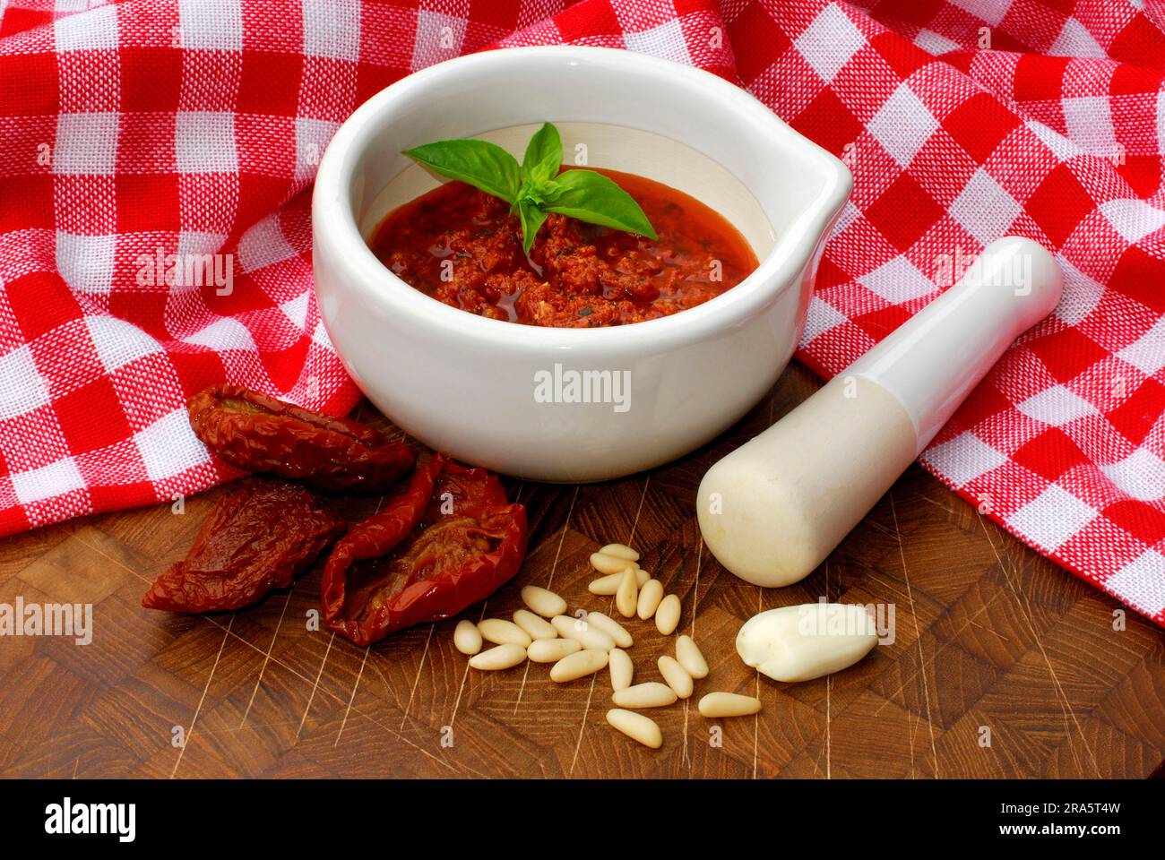 Tomato pesto in mortar with pestle, dried tomatoes, pine nuts, garlic