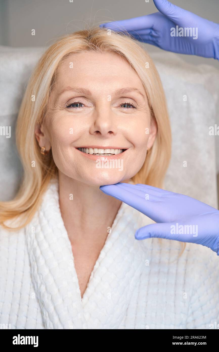 Hands in medical gloves holding smiling woman head Stock Photo