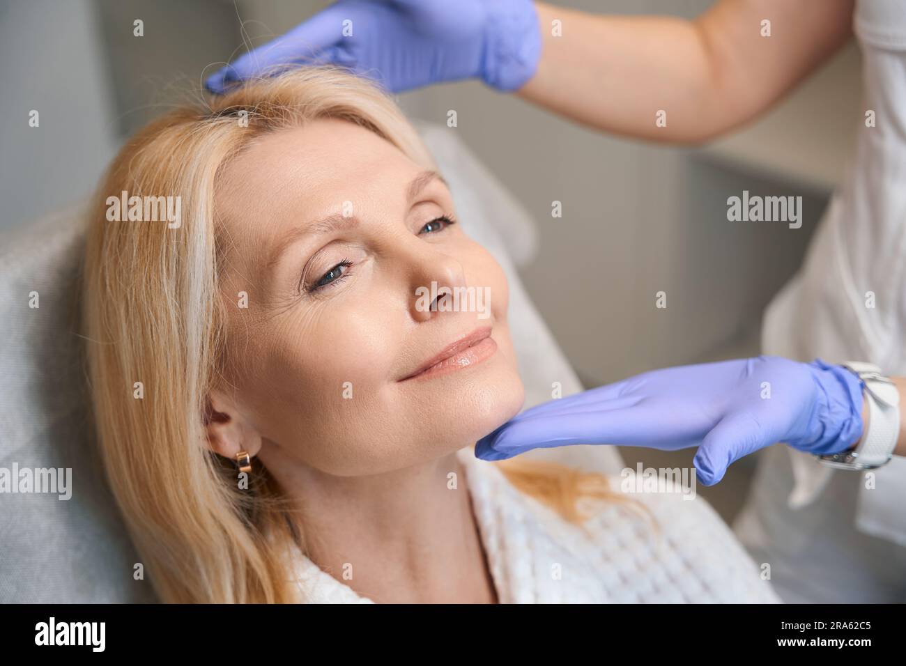Hands in medical gloves holding happy woman head Stock Photo