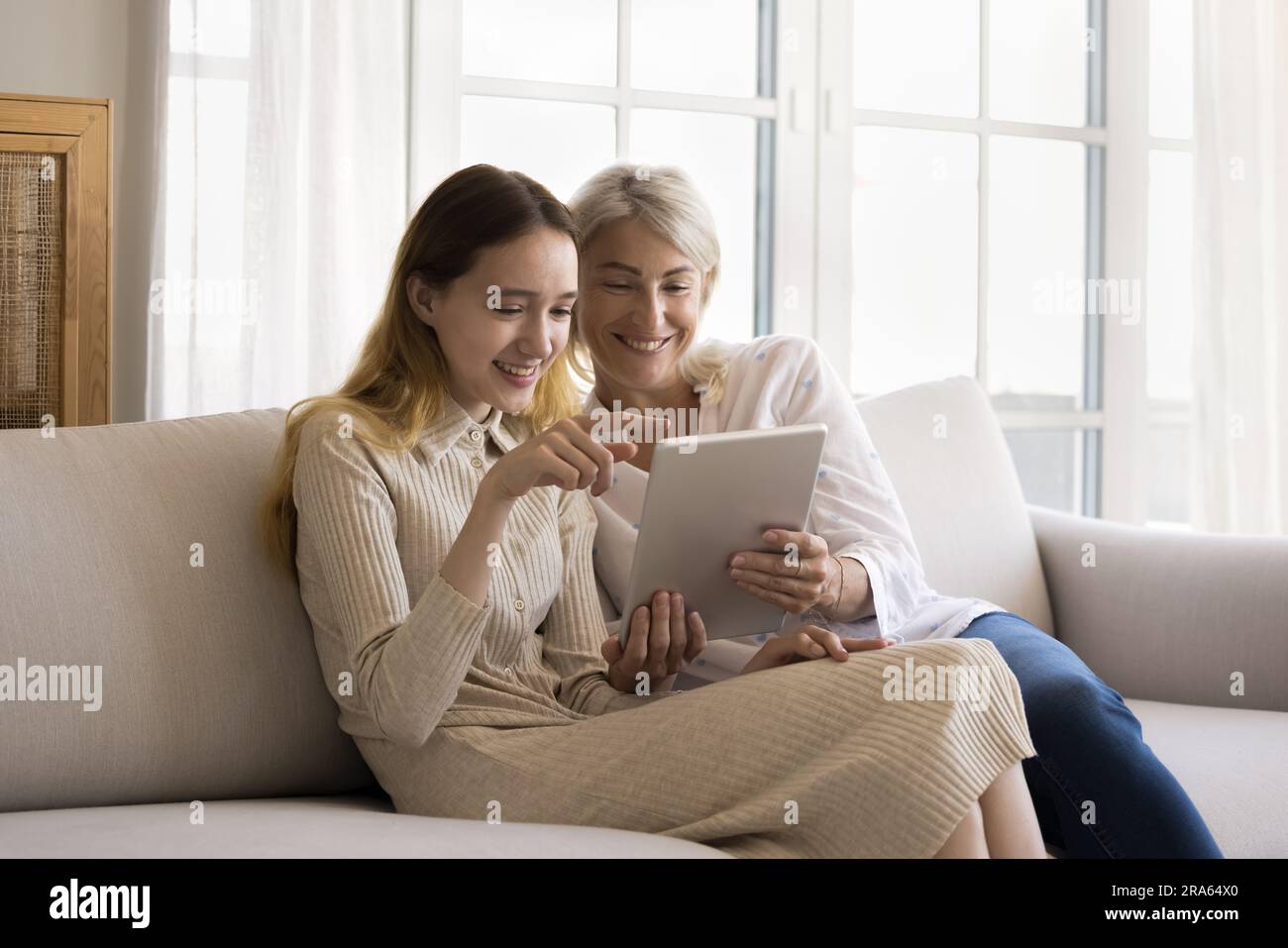 Positive smart teenager girl and pretty grandma enjoying modern ...