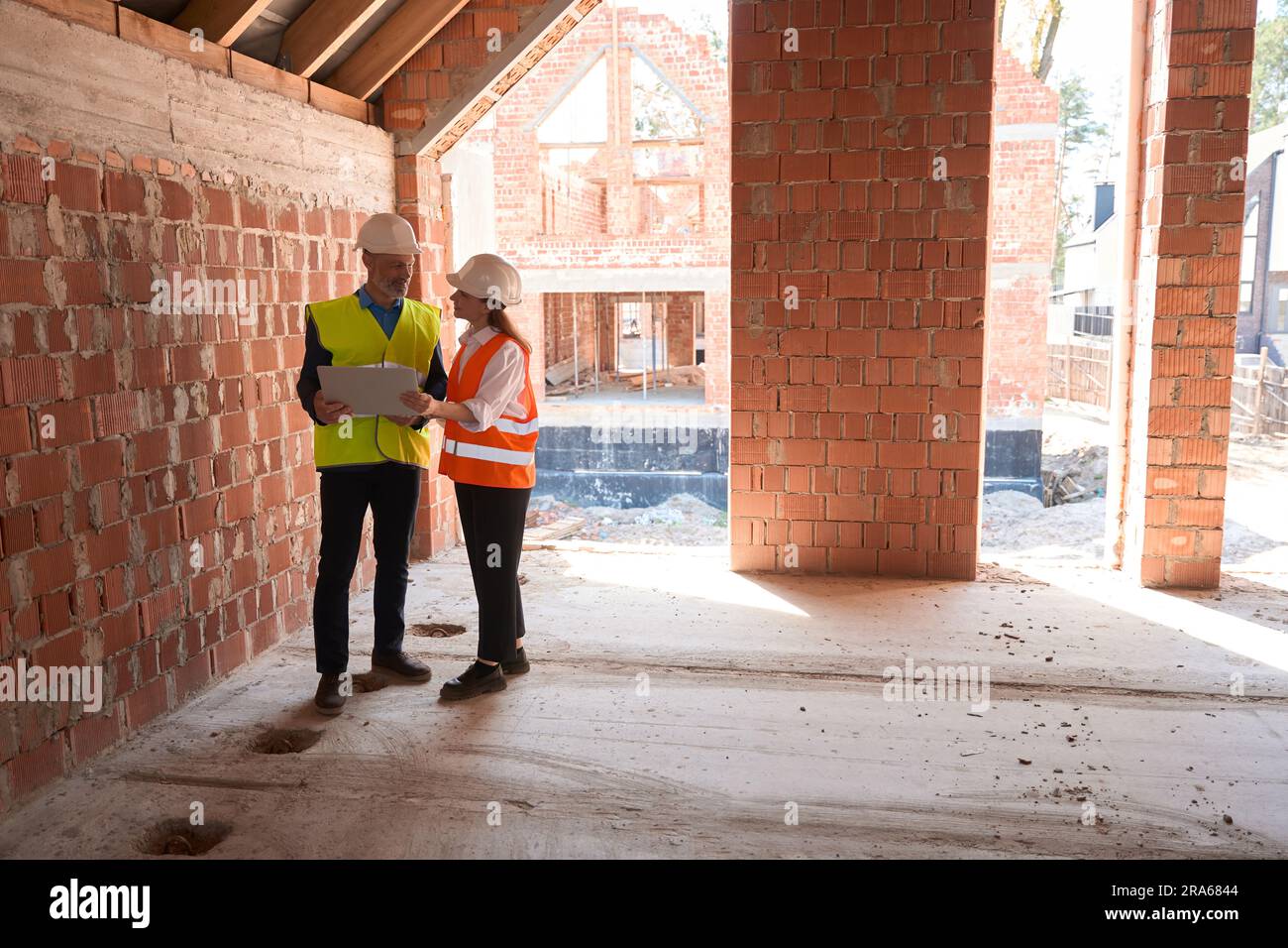 Building engineers standing inside building with laptop Stock Photo - Alamy