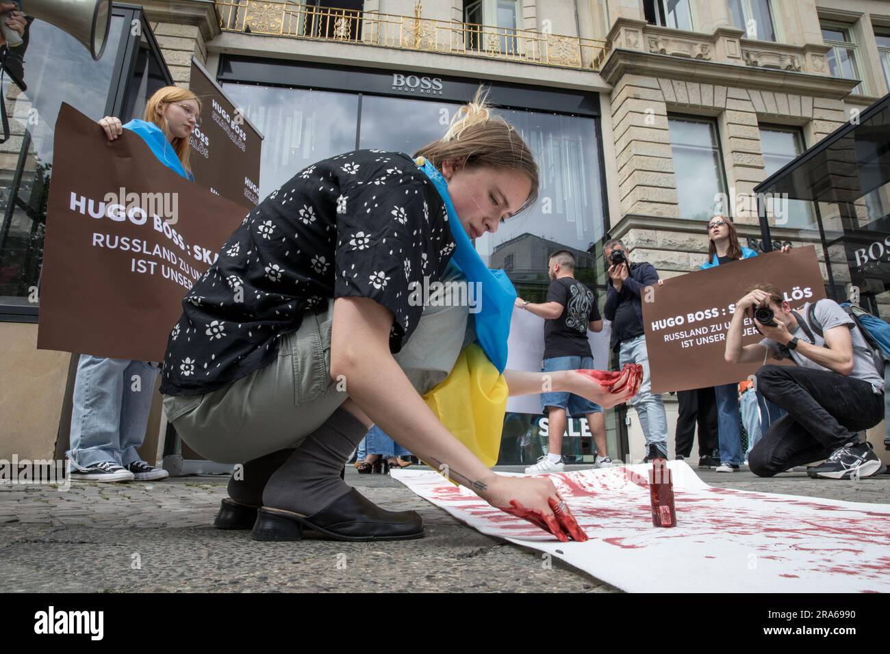 In Berlin, the Hugo Boss store, a beacon of German luxury fashion, became  the stage for a protest on July 1, 2023. Draped in Ukrainian flags,  Protesters gathered in front of the
