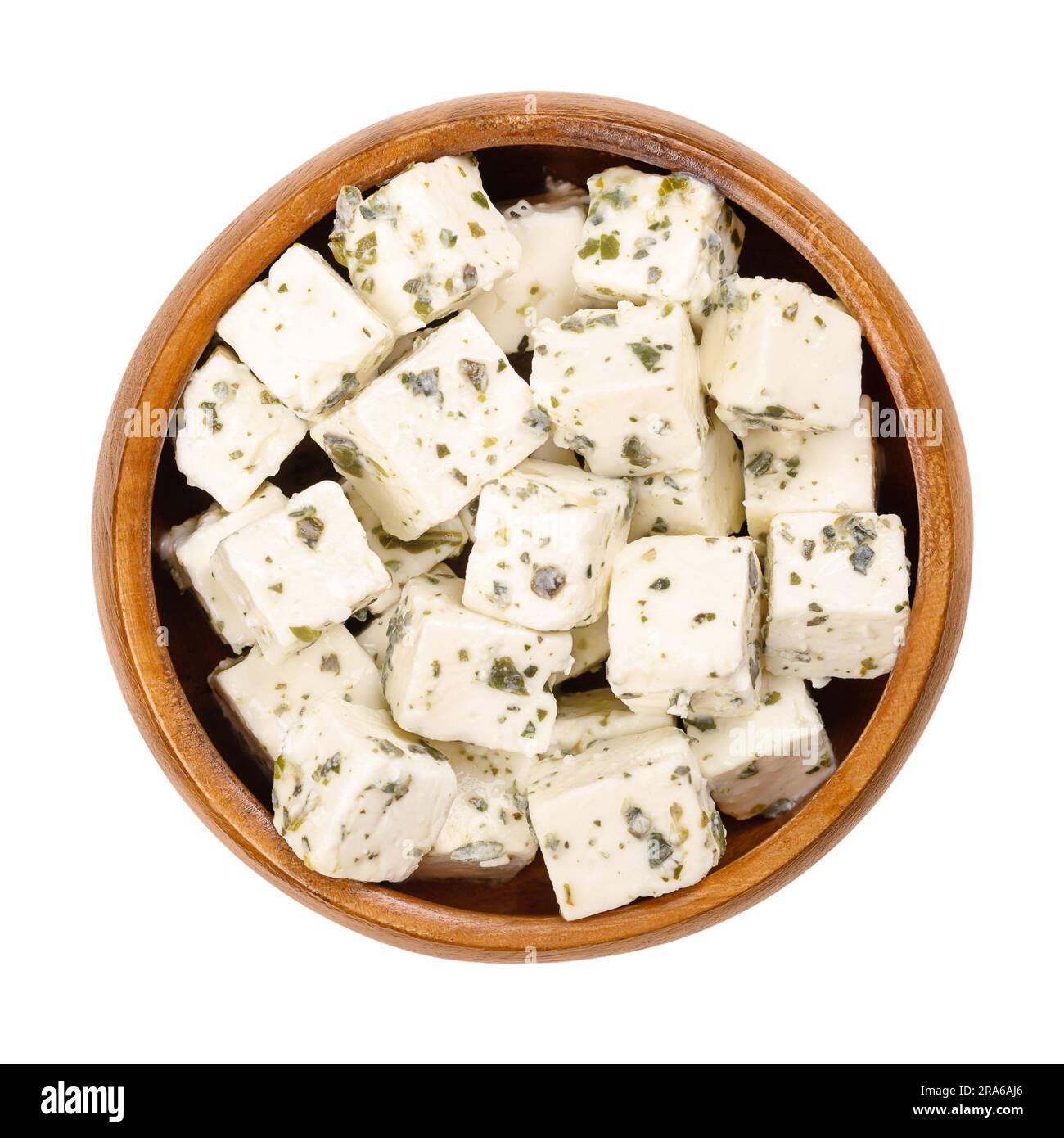 Greek feta cubes, brined cheese with Mediterranean herbs, in wooden bowl. Cheese, matured in brine, with soft and moist texture, fresh and salty taste. Stock Photo
