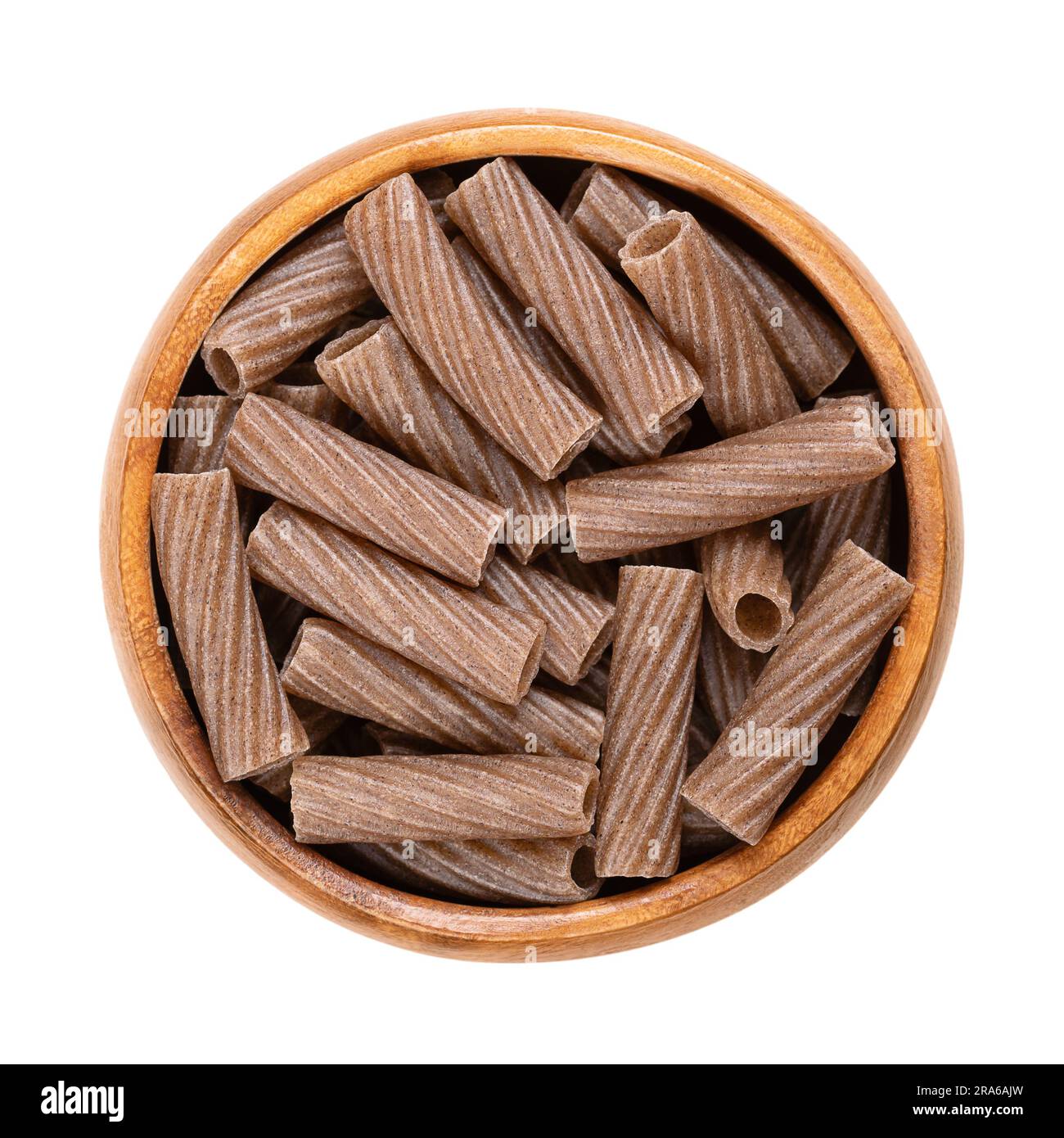 Buckwheat tortiglioni, gluten free whole grain pasta, in a wooden bowl. Dark brown dried noodles made of buckwheat semolina, extruded into cylinders. Stock Photo