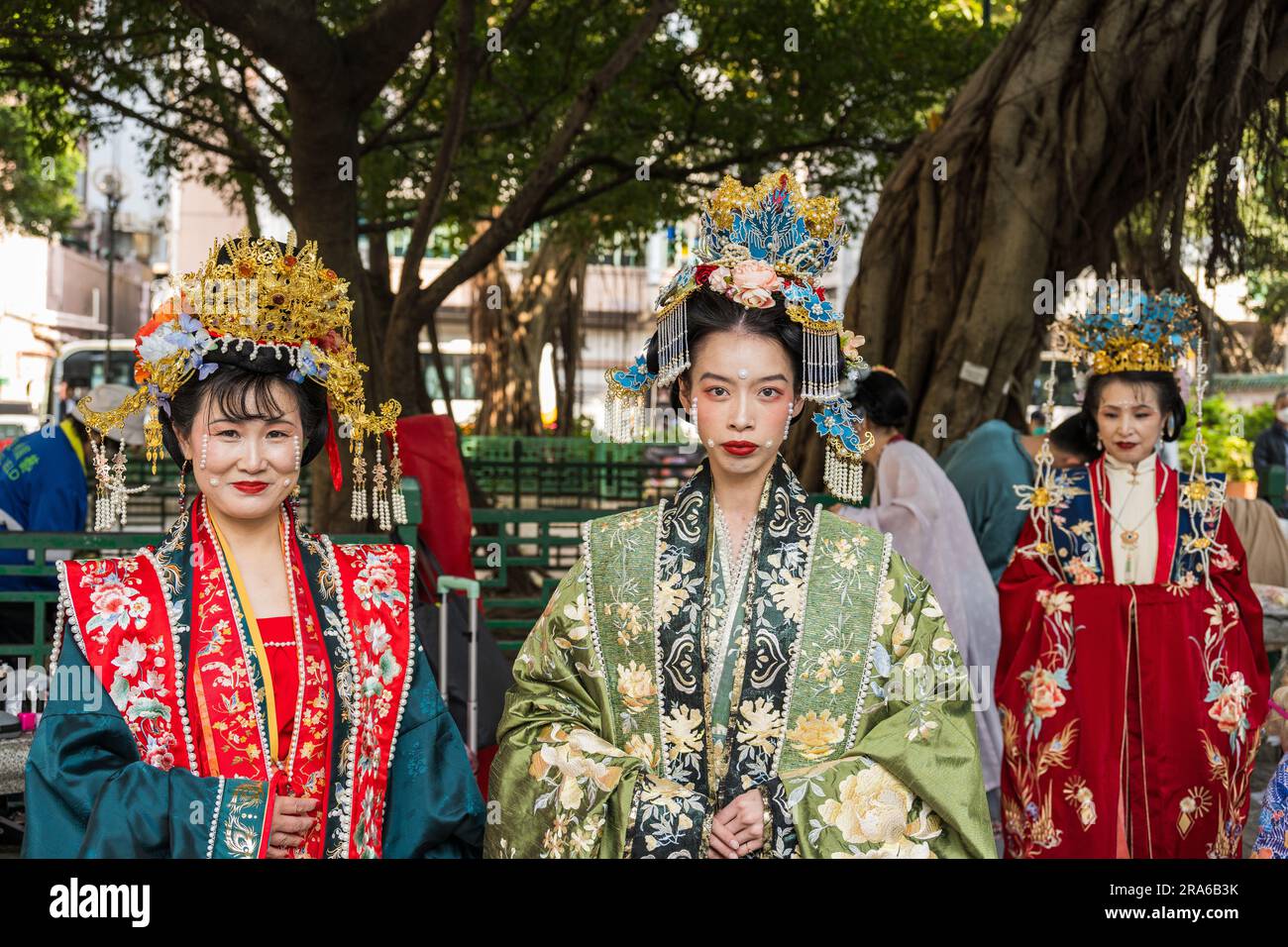 Hong Kong, China -- March 11, 2023. Three Chinese women in a park wearing traditional wedding clothing. Stock Photo