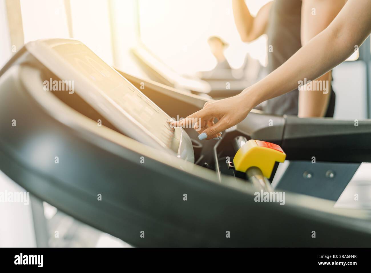 Healthy fitness girl running on treadmill sport club, closeup finger setting speed and climb level in control panel. Stock Photo