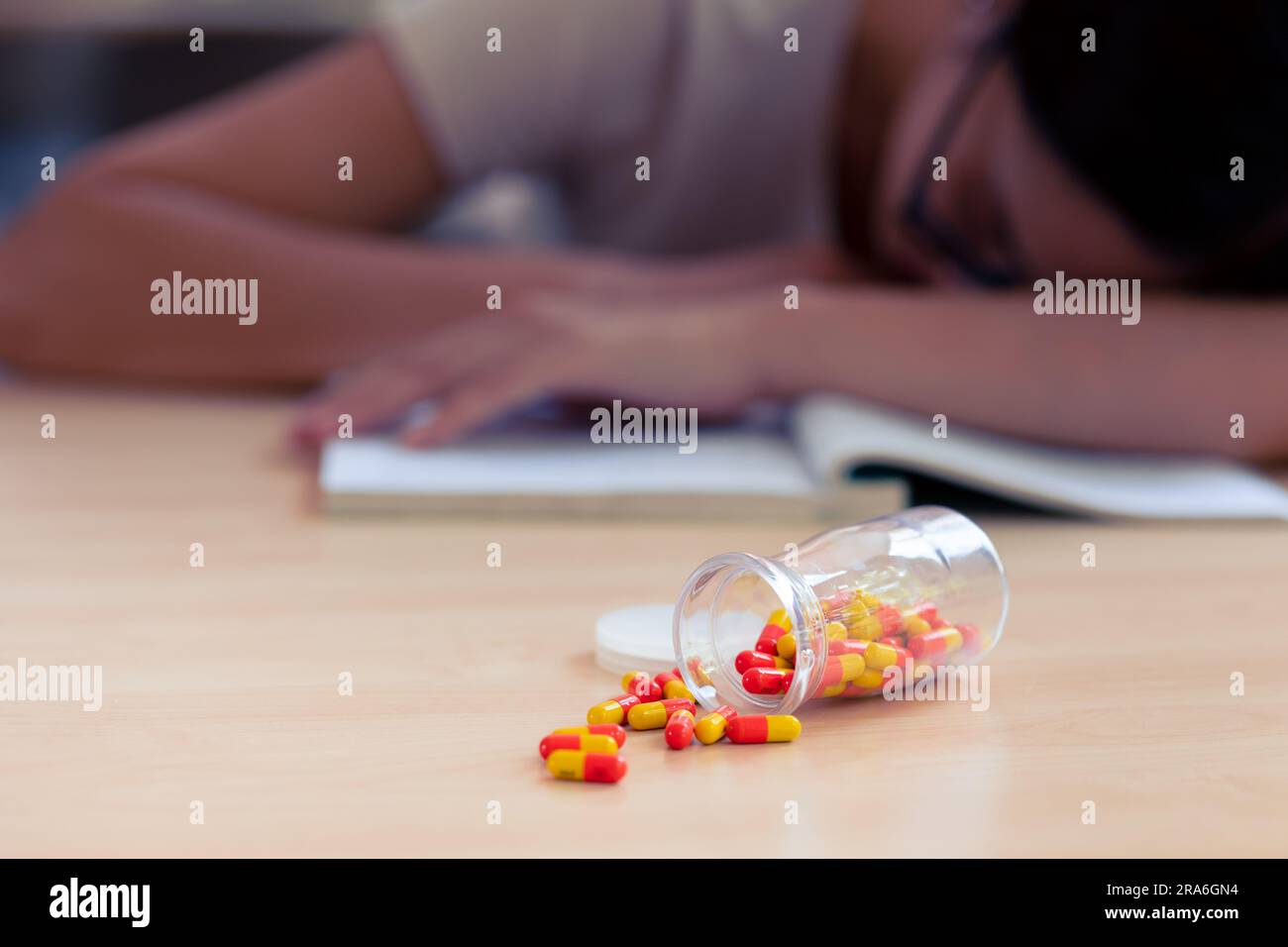 Young teen student with medicine drug capsule pill for pain relief or reduce stress from studying hard. Stock Photo