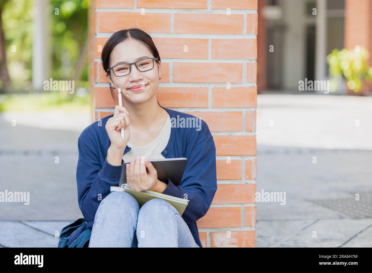 University Asian teen girl sitting happy smile in school campus. student with tablet computer. Stock Photo