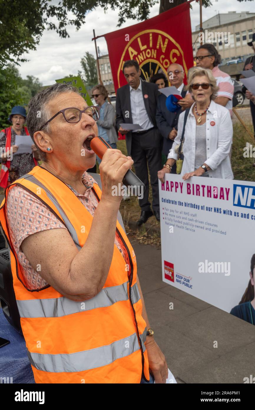 London, UK. 1 July 2023. Eve Turner, Ealing Save Our NHS, leads some singing. Campaigners from Ealing Save Our NHS celebrated 75 years of the NHS on the side of the main road in front of Ealing Hospital. Speakers called for a proper workforce plan, pointing out the failure of the recent government plan to recognise the realities of an overworked and underpaid system which has been deliberately run into the ground as a pretext for privatisation. Peter Marshall/Alamy Live News Stock Photo